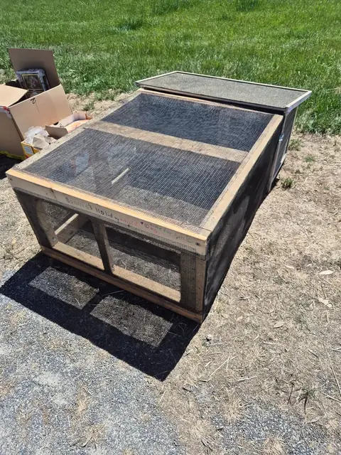 A large timber and wire mesh animal hutch with a hinged lid.