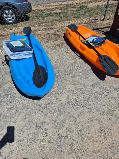 Two sit-on-top kayaks, one blue and one orange, with their paddles.